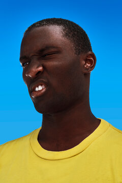 African American young man squinting in the sun.