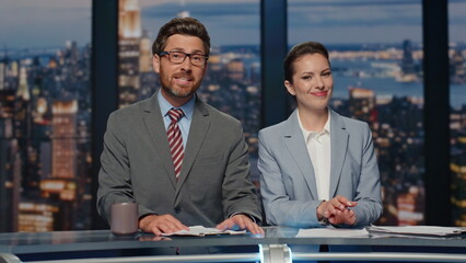 Smiling anchors broadcasting news at evening television media channel closeup
