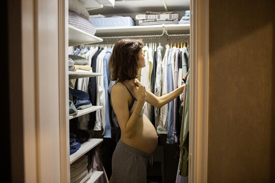 Pregnant woman choosing clothes at the wardrobe at home