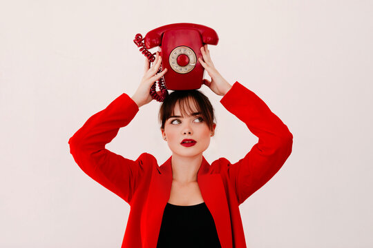 Stylish young woman holding retro telephone handset on head
