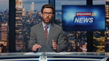 Bearded newscaster ending program in evening newsroom studio. Late breaking news
