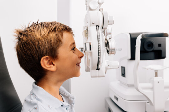Happy boy checking eyesight with professional phoropter