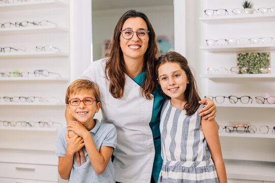 Glad optician with children in glasses in optics salon