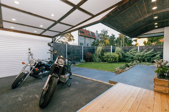 Motorbikes parked in an open garage in a landscaped house backyard