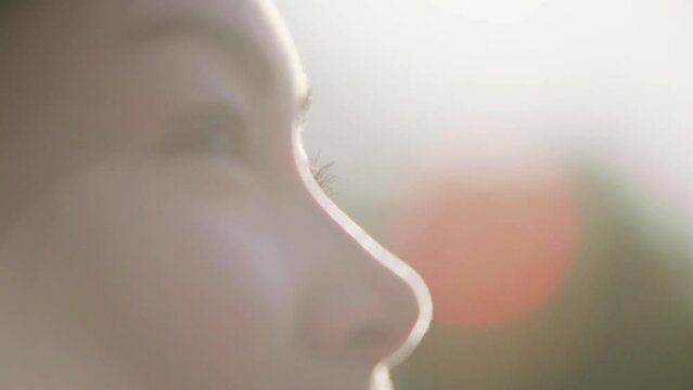 Close up profile on the eyes of a young woman, standing outside in the sun. Steadicam shot wraps in and out of focus.