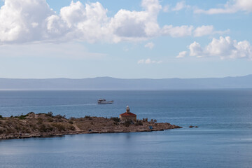 Scenic view of lighthouse Svjetionik Sveti Petar in port of coastal town Makarska, Dalmatia, Croatia. Fishermen boat along majestic coastline of Adriatic Mediterranean Sea. Tranquility