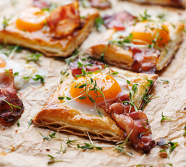 Puff pastry egg and bacon mini tarts  sprinkle fresh cress, focus on the tart in middle, close up view. Delicious breakfast or Easter snack - 759167418