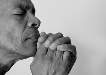 man praying to god with hands together worshiping God Caribbean man praying with people stock image stock photo	