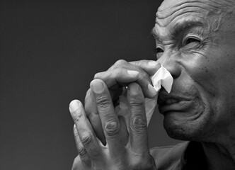 catching the cold and flu man blowing nose after catching a cold with grey background with people stock photo	