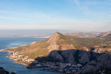 Scenic aerial view of coastal town Omis surrounded by Dinara mountains in Split-Dalmatia, South Croatia, Europe. Majestic coastline of Omis Riviera, Adriatic Sea in Balkans in summer. Dramatic sunrise