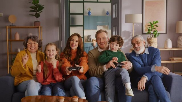 Family playing video game and raising hands after winning