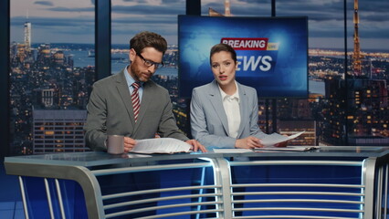 Confident anchors announcing news at evening modern studio closeup. Hosts talk