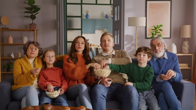 Six family members sharing popcorn in front of television