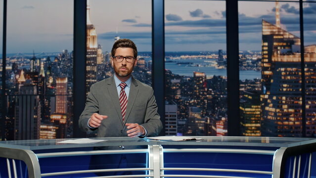 Serious anchor reporting events at newsroom. Presenter speaking at news desk