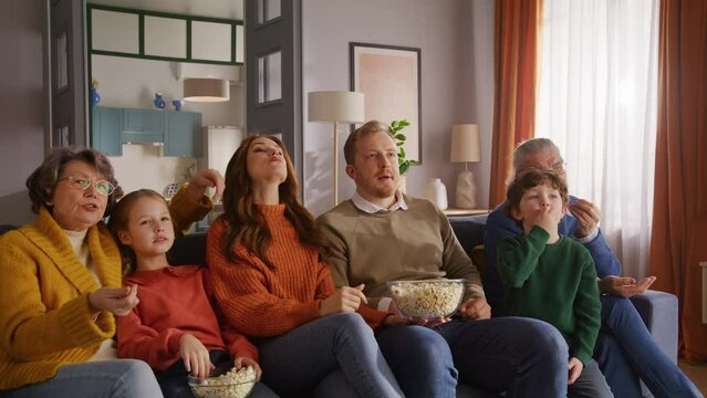Friendly family sitting on couch and pointing to tv screen