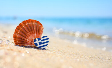 Sandy beach in Greece. Greece flag in the shape of a heart and a large shell. A wonderful seaside...