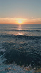 Idyllic sea sunset shining in deep blue ocean water aerial view. Waves foaming 