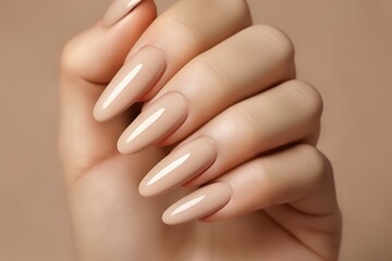 Fototapeta premium Glamour woman hand with nude nail polish on her fingernails. Nude shade nail manicure with gel polish at luxury beauty salon. Nail art and design. Female hand model. French manicure.