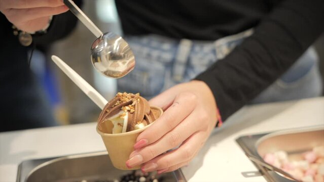 Woman pouring chocolate balls on vanilla ice-cream