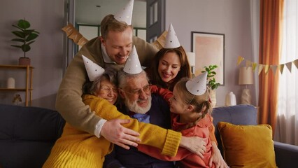 Grey male getting hugged by wife, grown up kids and girl