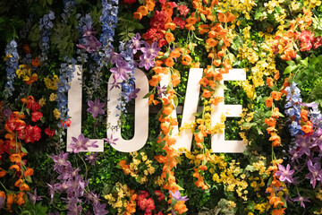 Schriftzug "LOVE" umhüllt von bunten Blumen