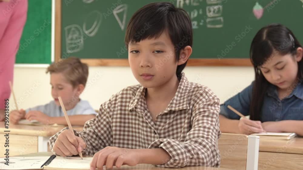 Aufkleber asian smart boy smiling to camera while student writing answer in answer sheet. multicultural studen