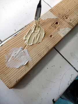Application of a polyester putty on a wooden hole with a spatula
