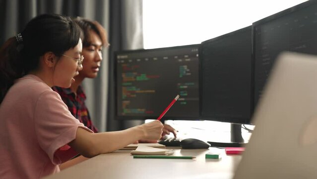 Slow motion back end software developer engineer for computer programming working together on debugging writing computing code, solving complex algorithms display on monitor in office. Burgeoning