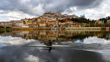 cidade de Coimbra refletida no rio Mondego e canoista