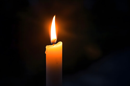 One lit candle on dark background