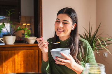 A young woman eating corn flakes for breakfast in the morning in her apartment	
