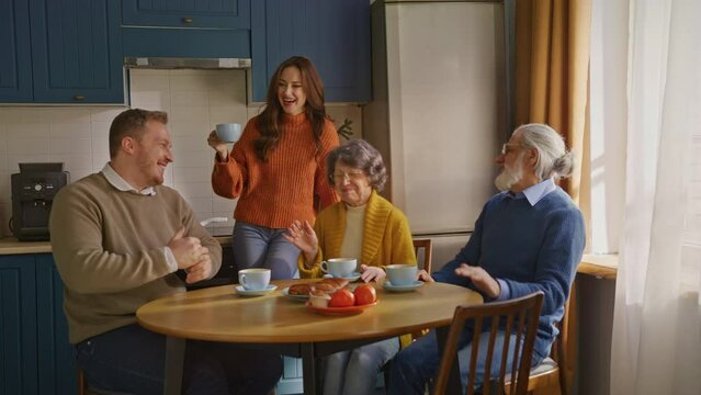 Blonde man making clap in front of laughing parents faces