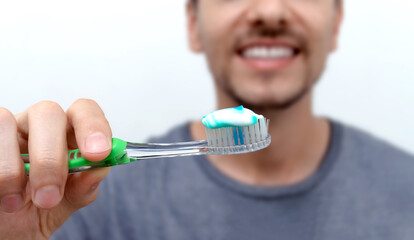 Hombre joven sonriente cepillando sus dientes. Higiene bucal con cepillo y pasta dental. Día...