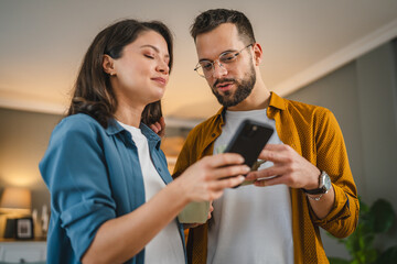 Adult couple man and woman husband wife have a cup of coffee use mobile phone search internet...