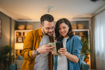 Adult couple man and woman husband wife have a cup of coffee use mobile phone search internet social network happy smile - obrazy, fototapety, plakaty