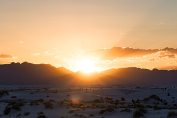 Sun rays peeking over the mountains and dunes of White Sands National Park, New Mexico during sunset © Tushar Turkar