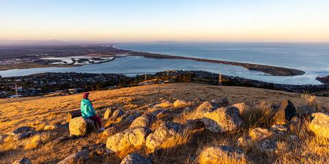 girl in colorful clothes enjoys the sunset over christchurch city from the hills at john britten...