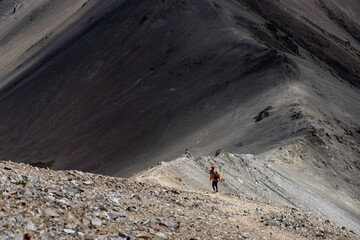 hiker girl walking down a very steep rocky hill from the summit of castle hill peak, torlesse...