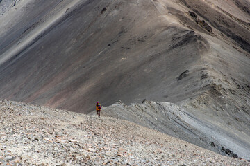 hiker girl walking down a very steep rocky hill from the summit of castle hill peak, torlesse...