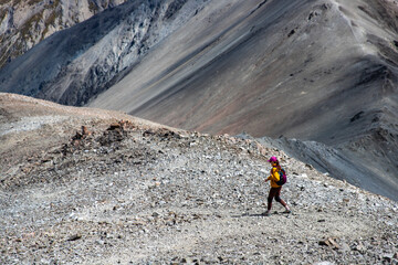 hiker girl walking down a very steep rocky hill from the summit of castle hill peak, torlesse...
