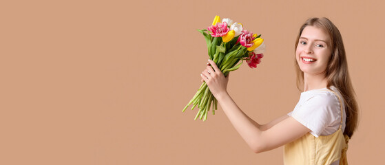 Happy young woman with bouquet of beautiful tulips on brown background