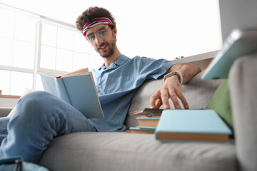 Male student reading book at home