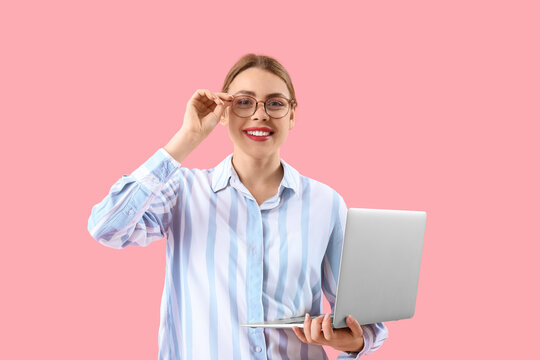 Female programmer with laptop on pink background