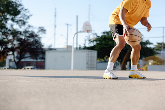 Man dribbling basketball outside.