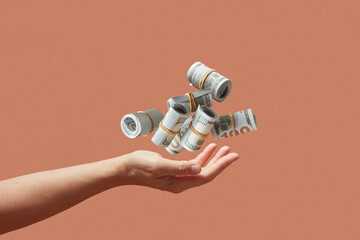 Female hand catching falling bundles of hundred dollar money