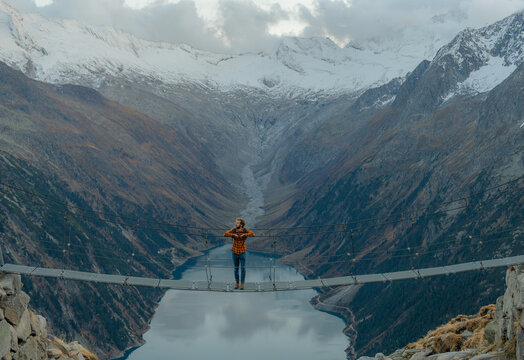 Man passing the bridge above the lake in Alps 