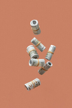 Dollar banknotes rolled up with rubber band falling in studio