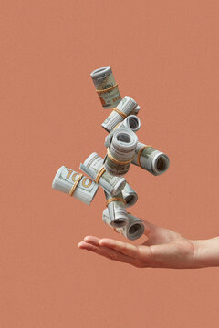 Female palm with levitating dollar banknotes over brown background