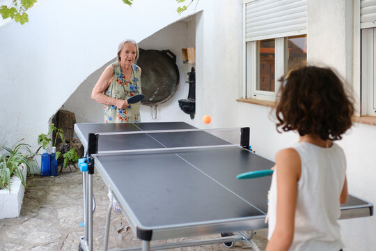Senior woman playing ping pong outdoor with granddaughter