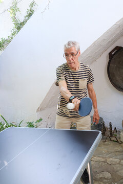 Senior man playing ping pong in home patio